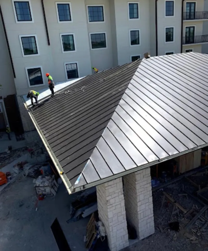 Crew installing standing seam metal roof panels on a commercial project in Antwerp